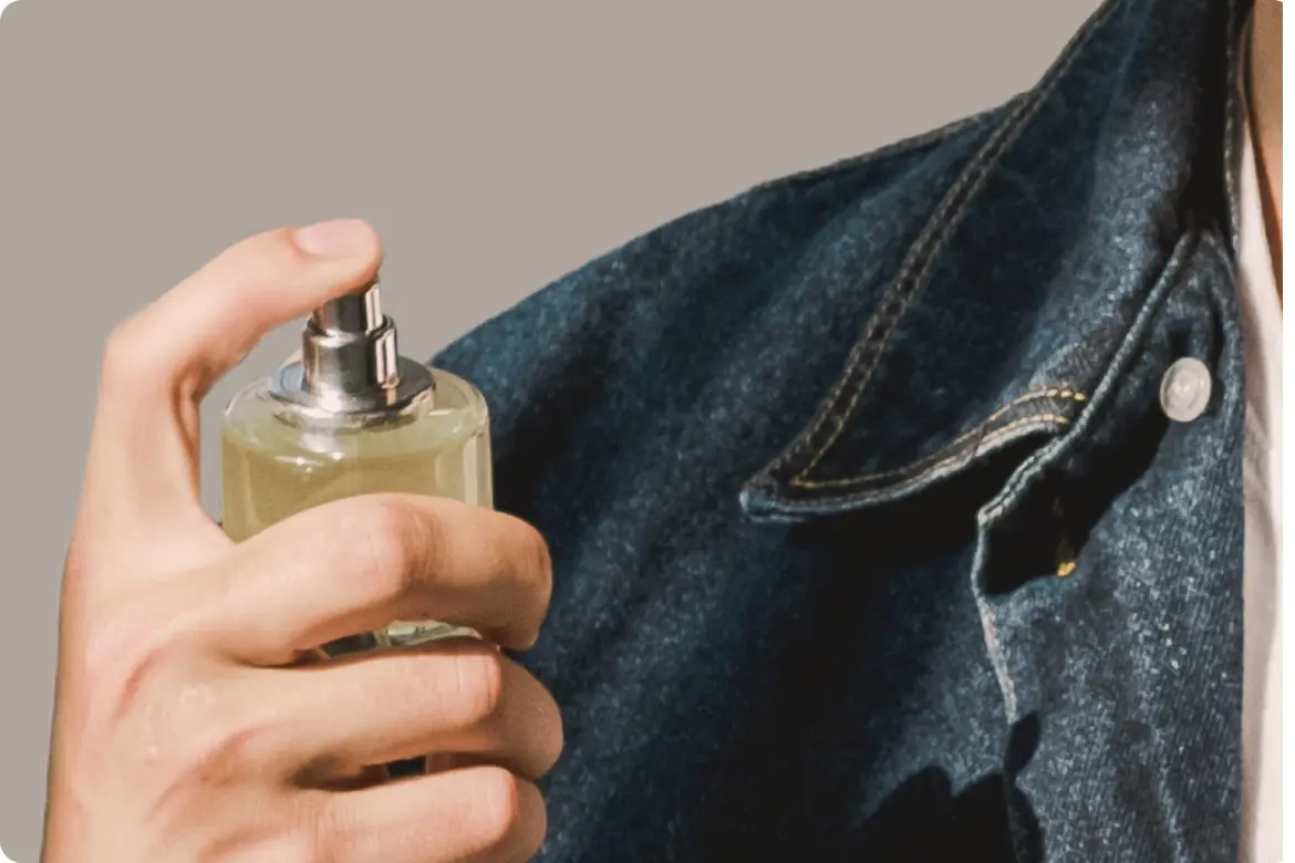 Man applying perfume to a denim jacket, representing long-lasting fragrances for men