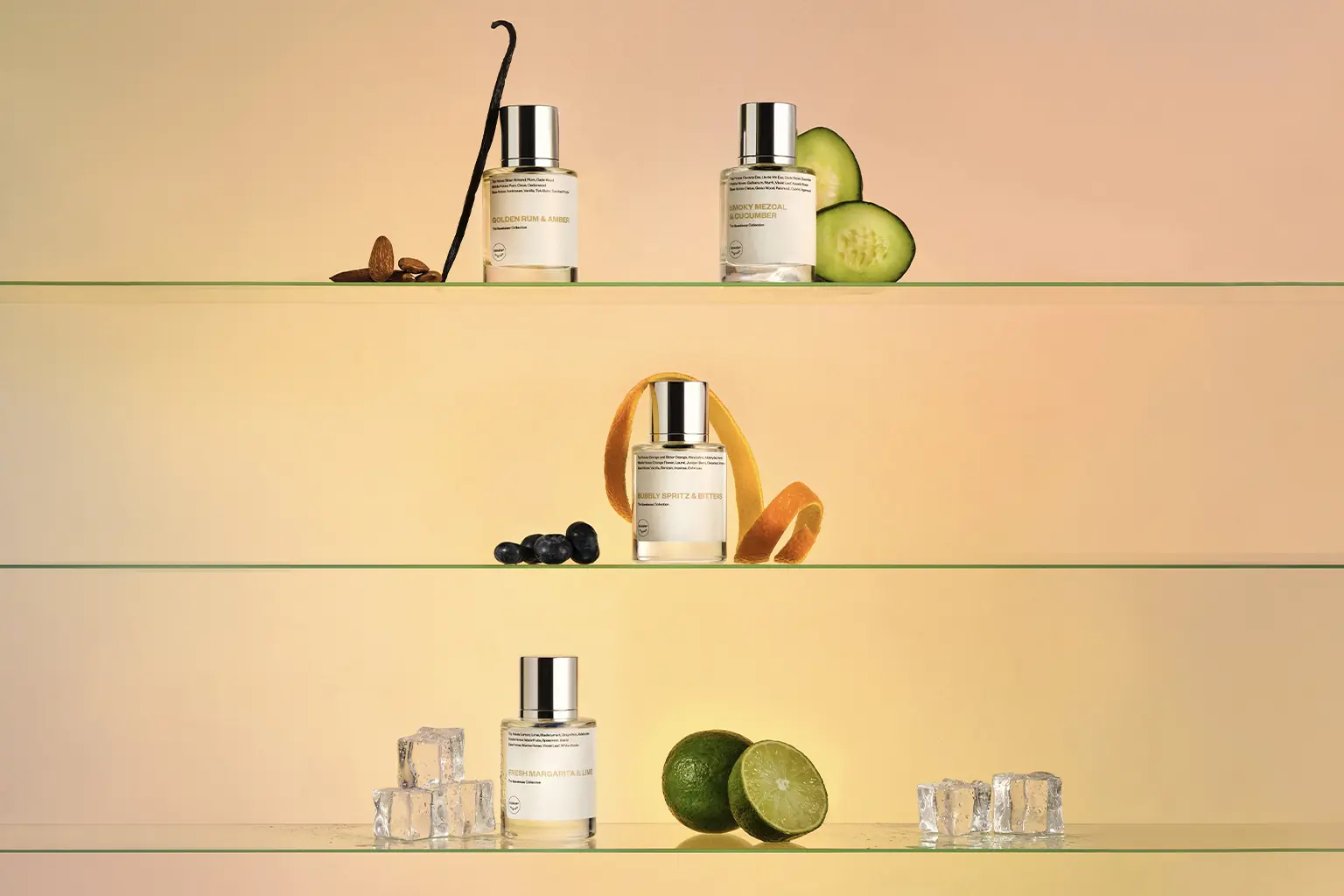 Four Dossier cocktail-inspired perfume bottles displayed with vanilla, cucumber, blueberries, citrus peel, limes, and ice on glass shelves against a warm gradient background.