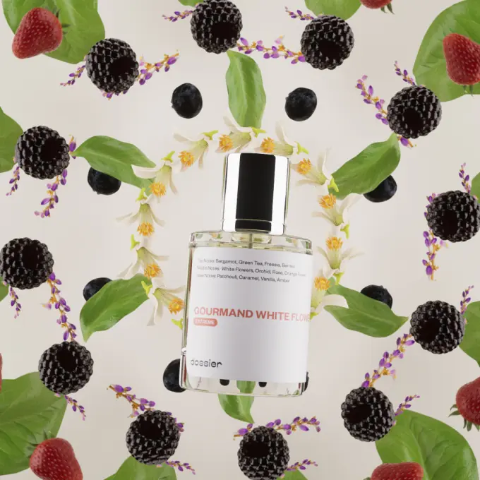 Dossier Gourmand White Flowers perfume bottle surrounded by blackberries, strawberries, green leaves, white blossoms, and delicate purple flowers.