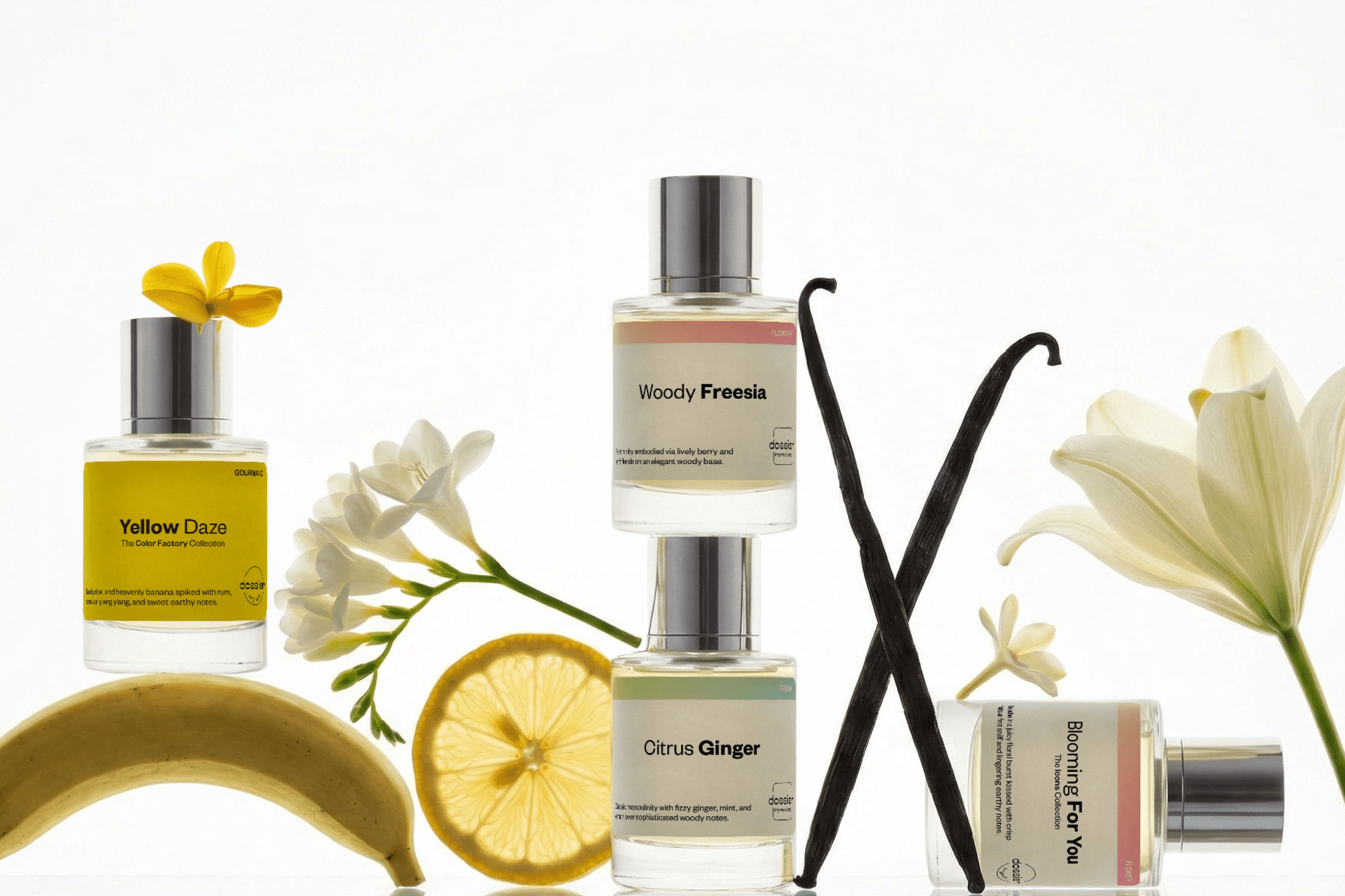 Perfume bottles including Yellow Daze, Woody Freesia, Citrus Ginger, and Blooming For You arranged with flowers, vanilla pods, lemon slice, and banana