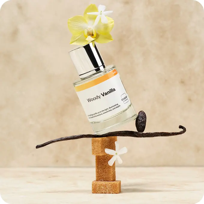 Dossier Woody Vanilla perfume balanced with vanilla pods, a vanilla bean, and yellow and white flowers.